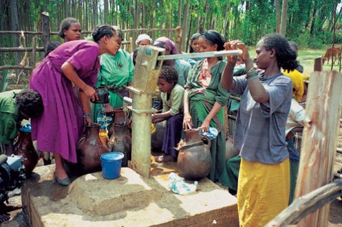 Afrikanische Dorfbewohnerinnen und -bewohner pumpen Wasser aus einem Brunnen.